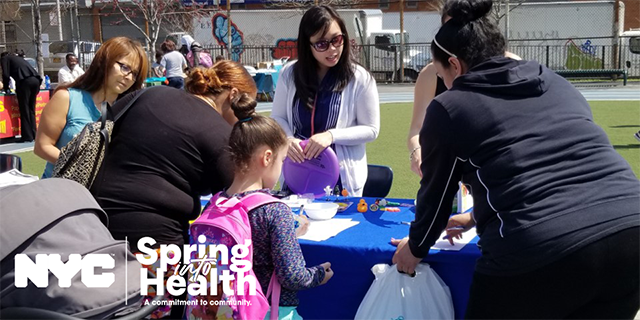 A mother and child visit a 2018 Spring Into Health exhibition table for community resources.